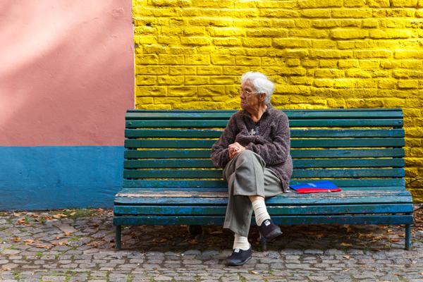 Eine alte Frau sitzt auf einer Bank am Caminito in La Boca